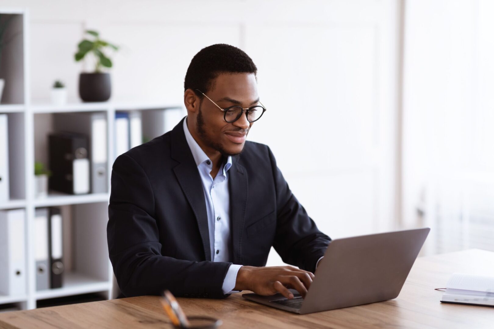 A man in suit and glasses using his laptop.